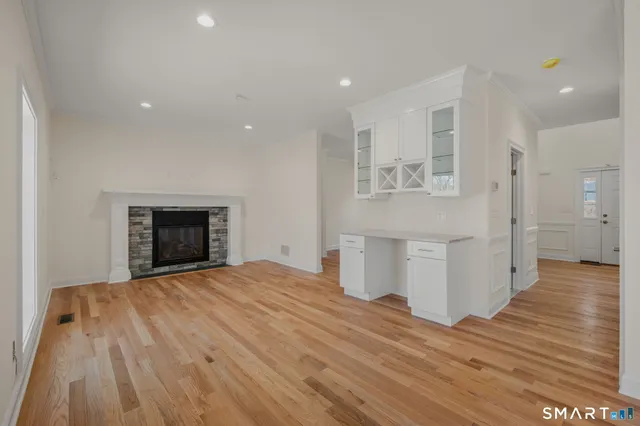 a view of an empty room with wooden floor and a fireplace