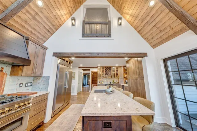 a kitchen with stainless steel appliances granite countertop a refrigerator a sink dishwasher a dining table and chairs with wooden floor