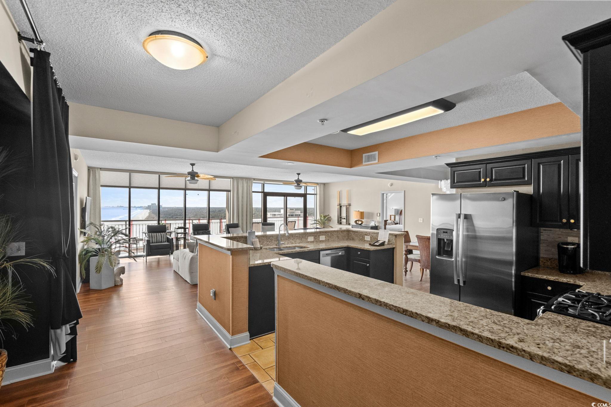 100 North Beach Boulevard, Unit 1803 North Myrtle Beach, SC 29582 - Photo 34 of 35 Kitchen featuring light stone counters, stainless steel appliances, light wood-style flooring, dark cabinetry, and open floor plan