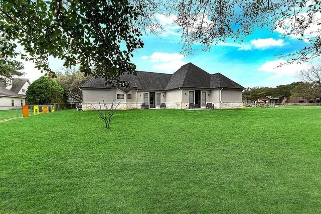 a white house with a big yard and large trees