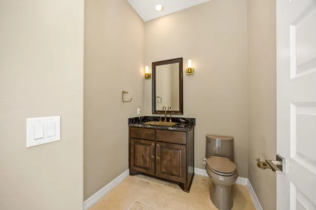 a bathroom with a granite countertop toilet and a sink