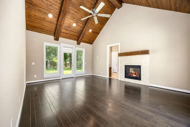 a view of an empty room with wooden floor and a fireplace