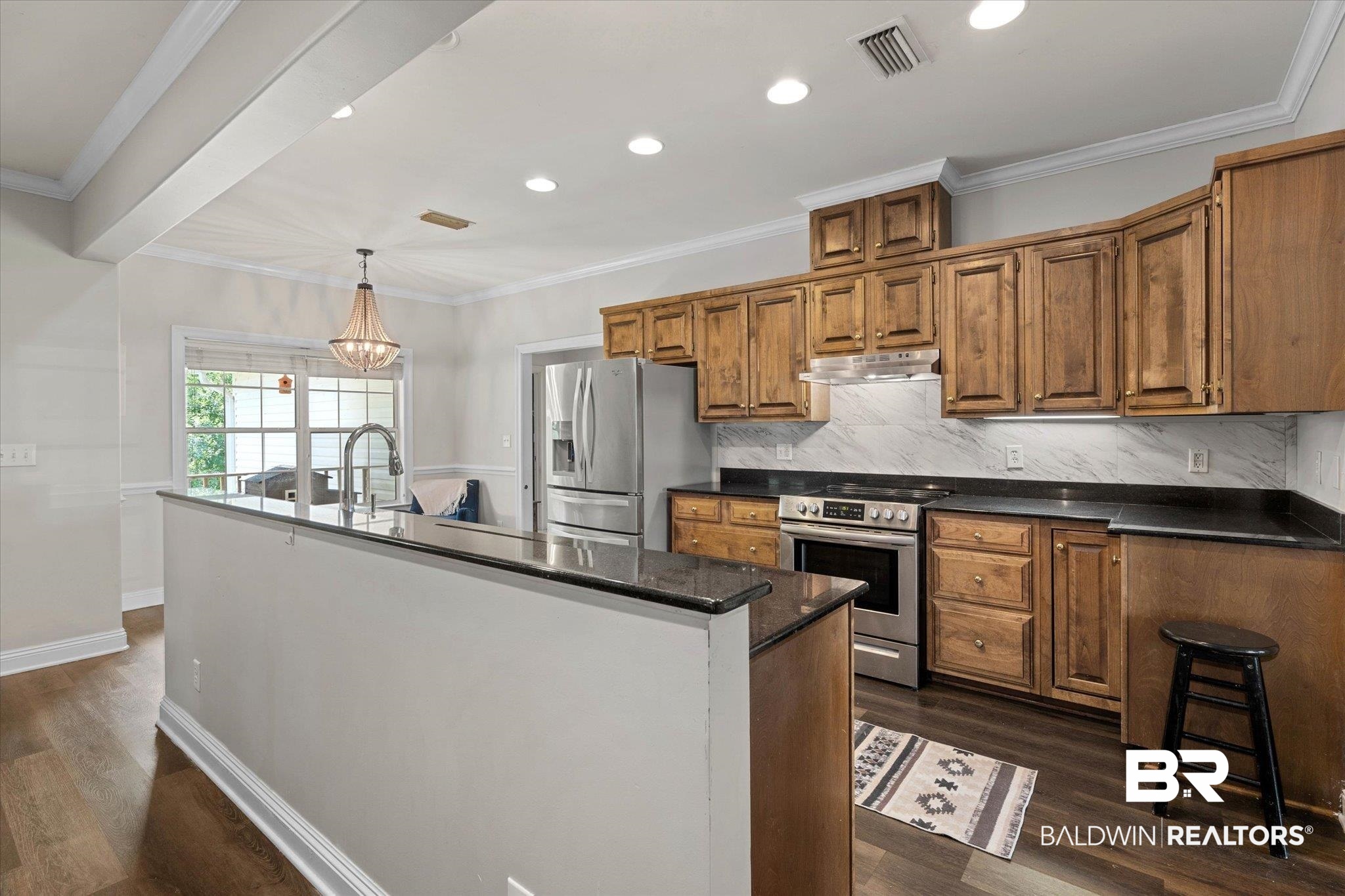 22760 Ridgewood Drive Robertsdale, AL 36567 - Photo 6 of 44 Kitchen featuring crown molding, backsplash, stainless steel appliances, brown cabinetry, and dark wood finished floors