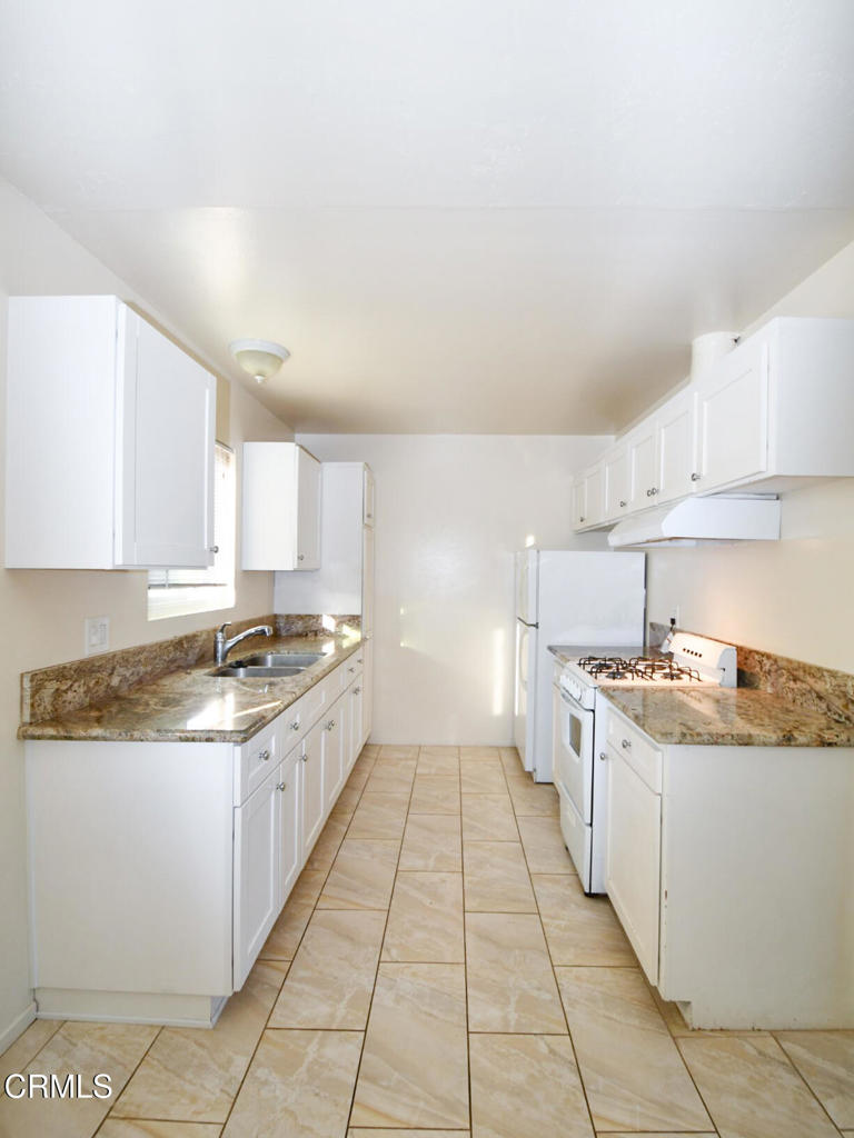 5009 Nautilus Street, Unit 14 Oxnard, CA 93035 - Photo 4 of 11 a large kitchen with granite countertop a stove top oven a sink a counter space and cabinets