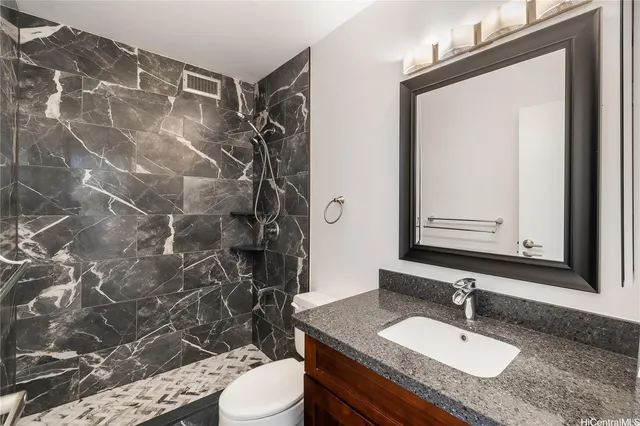 a bathroom with a granite countertop sink toilet a mirror and shower curtain
