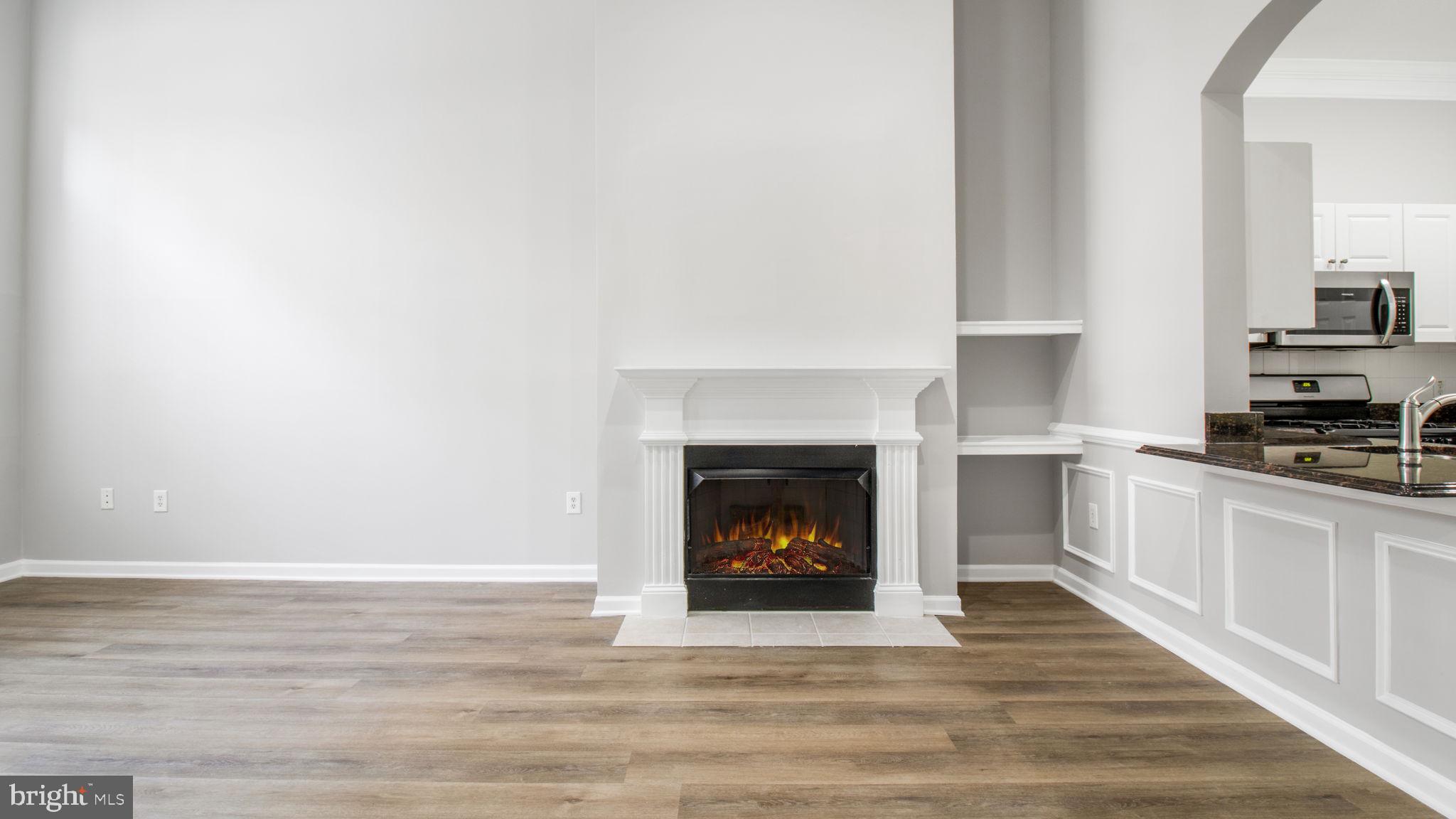 3 Arch Place, Unit 130 Gaithersburg, MD 20878 - Photo 6 of 45 a view of an empty room with kitchen and fireplace
