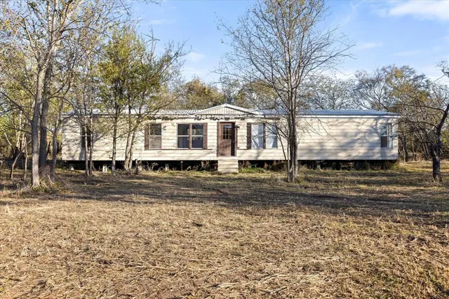 a front view of a house with a yard covered with trees