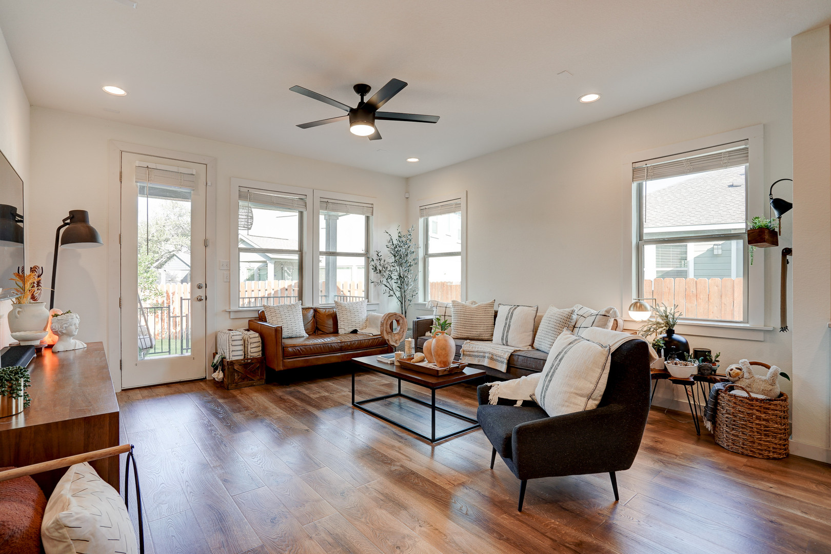 2240 Ringstaff Road Leander, TX 78641 - Photo 11 of 25 Expansive living area featuring wood-finish flooring, recessed ceiling lighting, a modern ceiling fan, multiple windows for natural light, and a glass-paneled exterior door