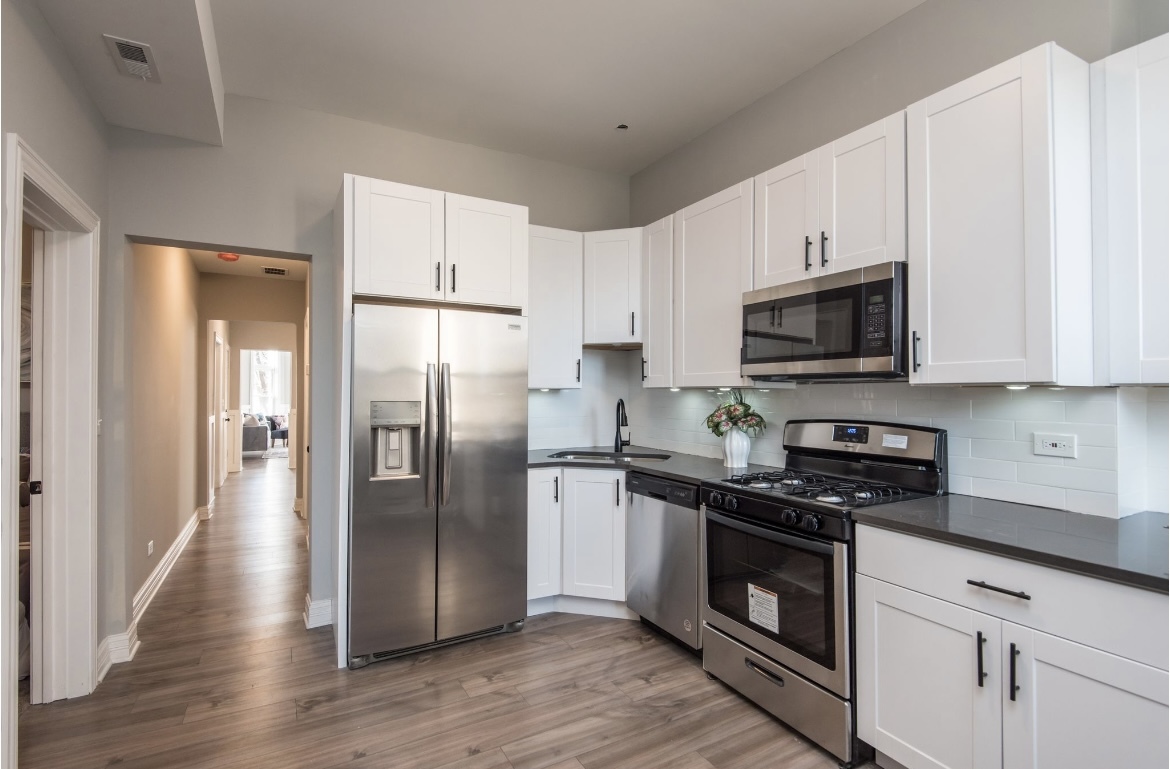 6607 South Ingleside Avenue Chicago, IL 60637 - Photo 17 of 28 a kitchen with stainless steel appliances granite countertop a refrigerator a stove top oven a sink and dishwasher with wooden floor