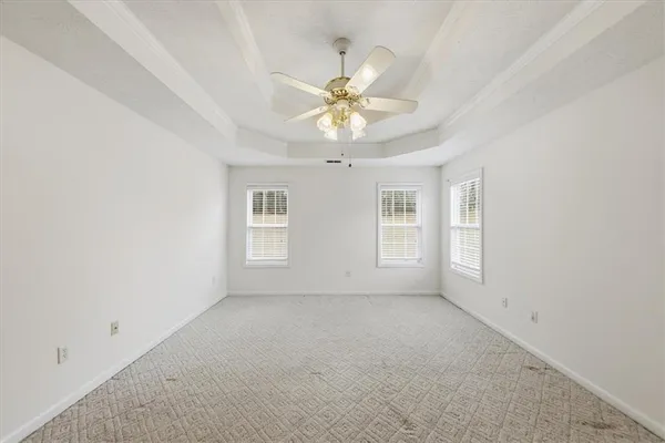 an empty room with a chandelier fan and wooden floor