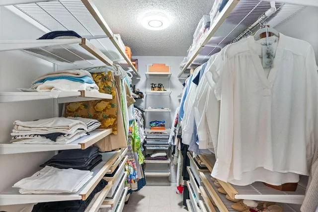 a view of walk in closet with clothes and shoes