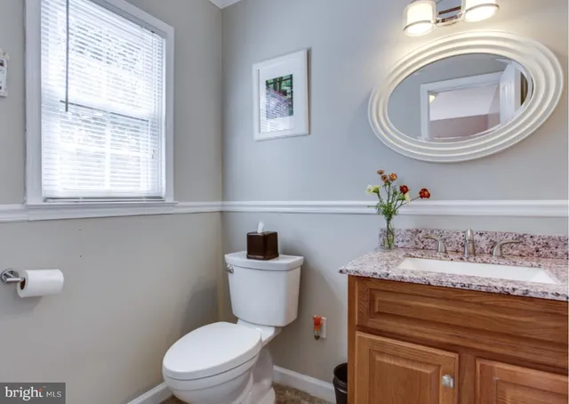 a bathroom with a granite countertop toilet a sink and a mirror