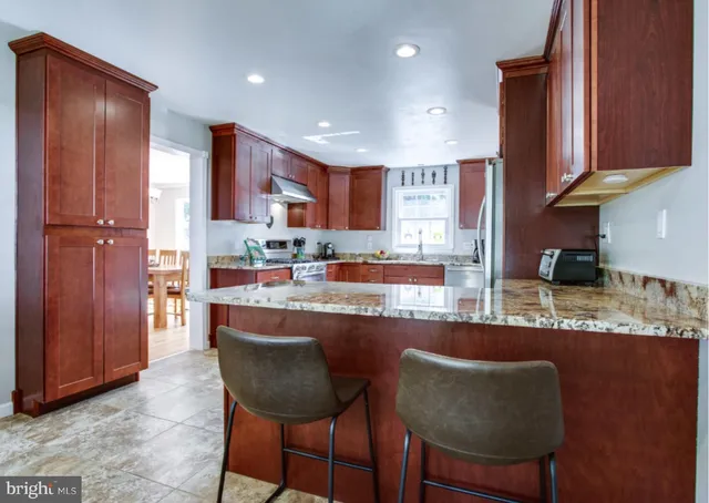 a kitchen with stainless steel appliances granite countertop table chairs sink refrigerator and cabinets