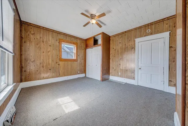 an empty room with ceiling fan and windows
