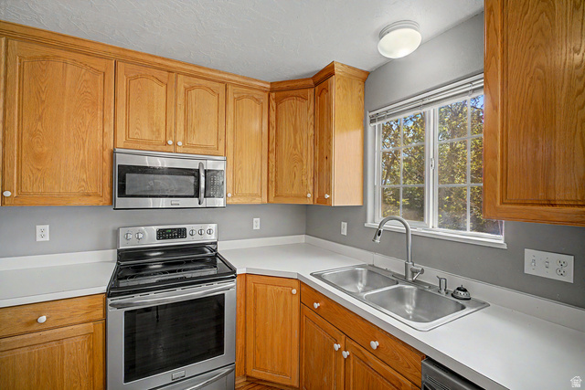 2058 California Avenue, Unit 2 Provo, UT 84606 - Photo 20 of 32 Kitchen featuring wood cabinetry, stainless steel appliances, white countertops, and a dual-basin stainless steel sink with a window overhead