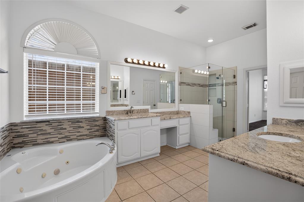 111 Ripplewood Coppell, TX 75019 - Photo 22 of 34 Spacious bathroom featuring a corner jetted tub, a separate glass-enclosed shower, dual vanity sinks with granite countertops, and tile flooring