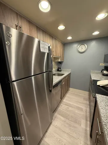 a kitchen with stainless steel appliances granite countertop a refrigerator a sink and a stove