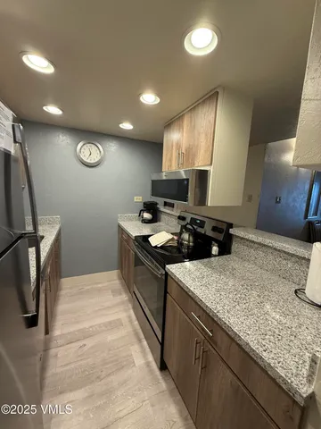 a kitchen with stainless steel appliances granite countertop a sink a stove and a wooden floors
