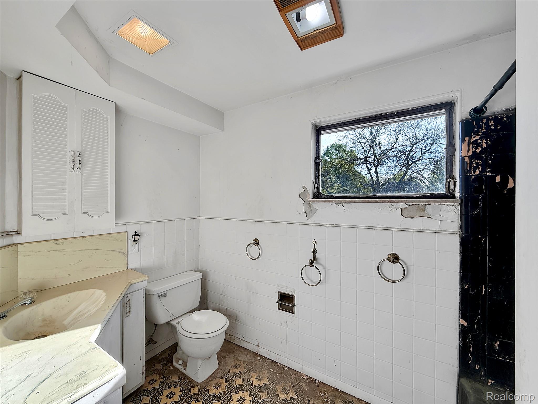 768 Washington Road Grosse Pointe, MI 48230 - Photo 15 of 54 Bathroom with vanity, a wainscoted wall, tile walls, and a closet
