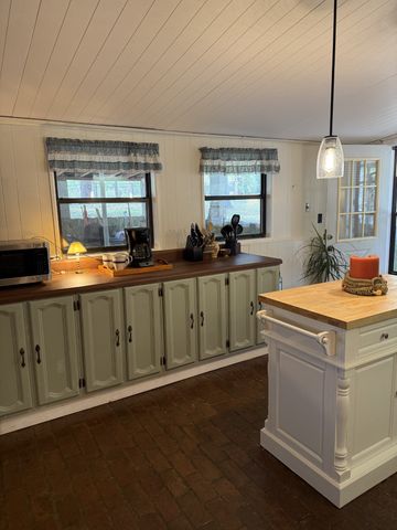 a view of a kitchen with a sink dishwasher a stove and a dining table with wooden floor