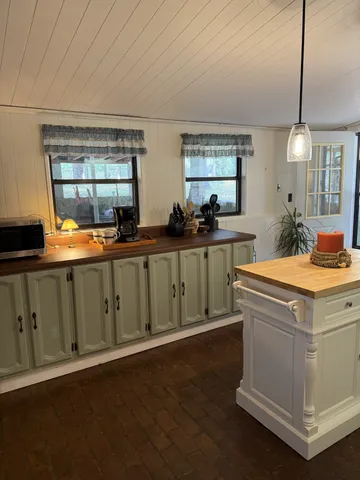 a view of a kitchen with a sink dishwasher a stove and a dining table with wooden floor