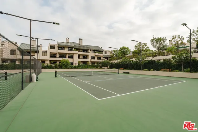 a view of a tennis ground with large trees