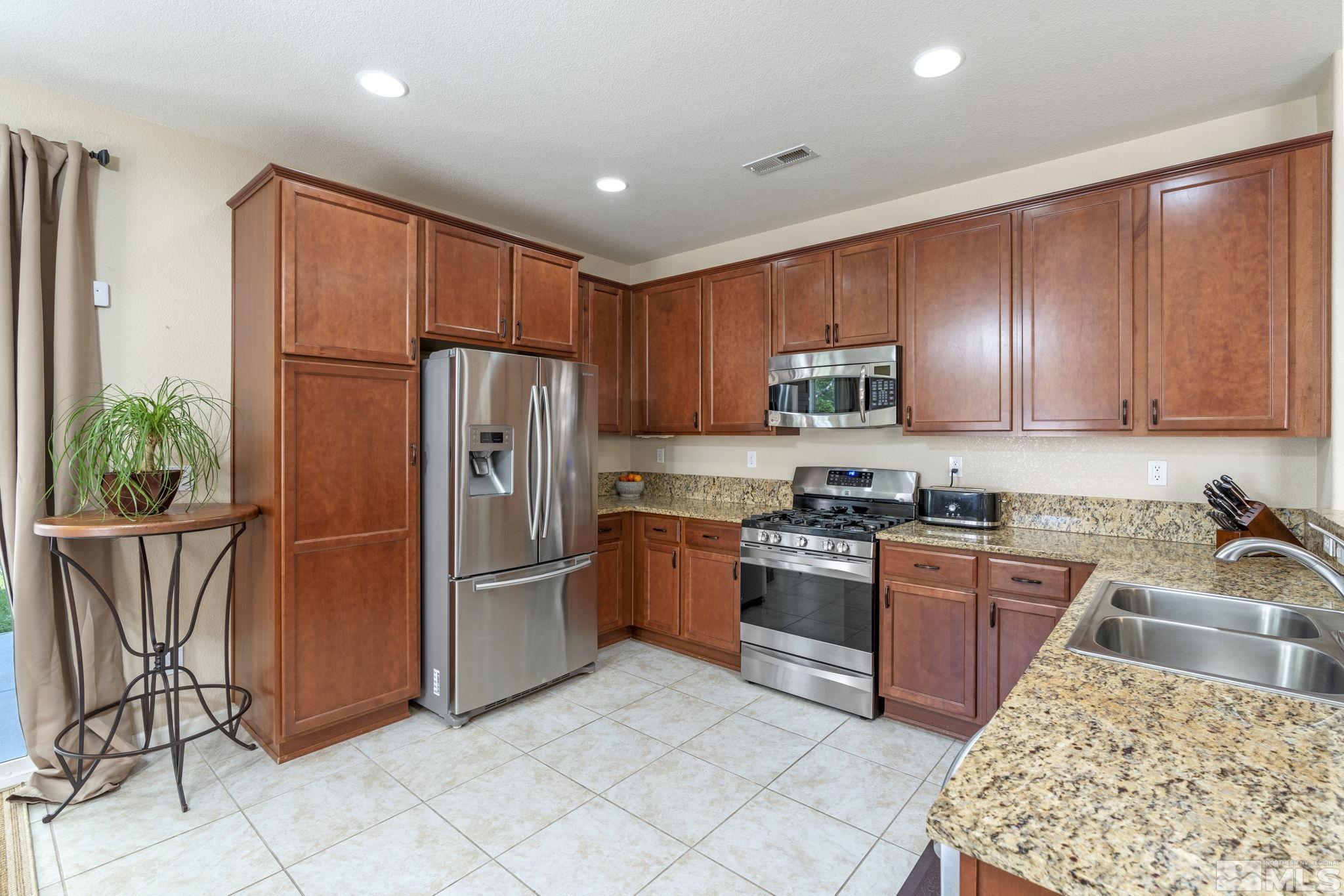 10848 Oakhaven Drive Reno, NV 89521 - Photo 13 of 32 a kitchen with stainless steel appliances granite countertop a refrigerator stove top oven and sink