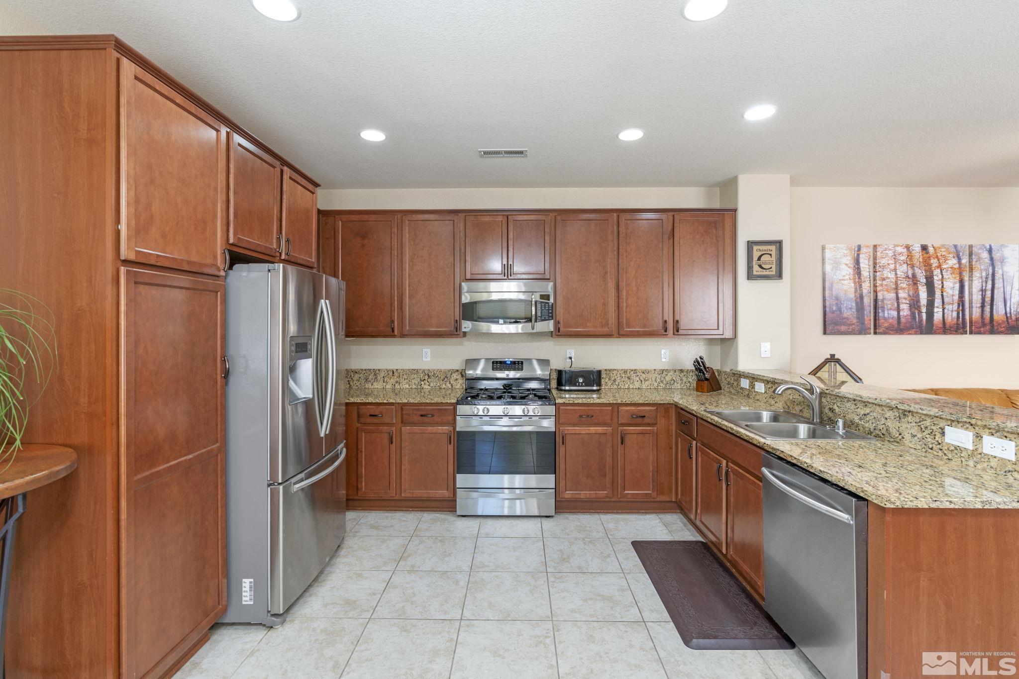 10848 Oakhaven Drive Reno, NV 89521 - Photo 14 of 32 a kitchen with stainless steel appliances granite countertop a refrigerator stove and sink
