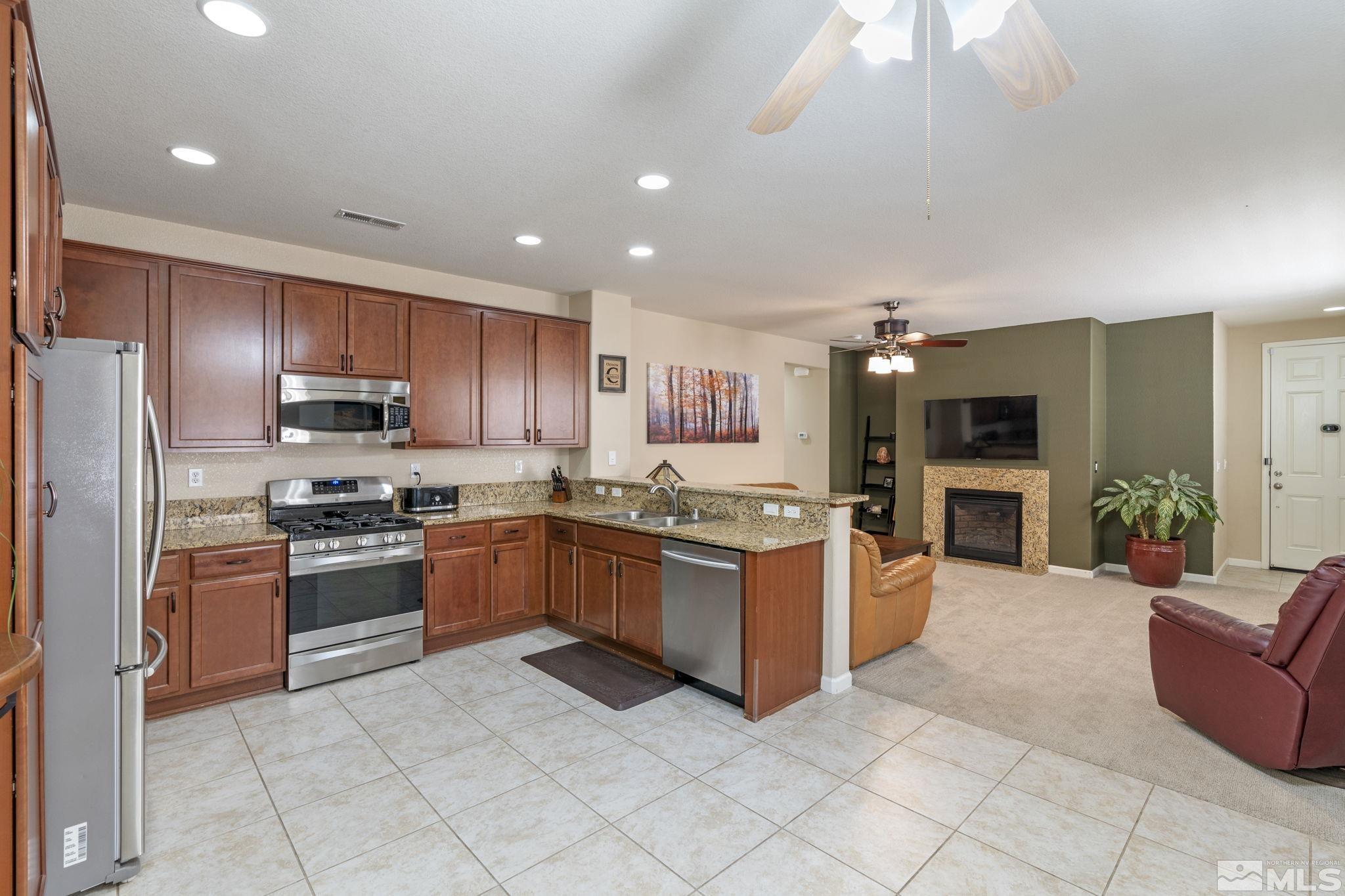 10848 Oakhaven Drive Reno, NV 89521 - Photo 15 of 32 a kitchen with stainless steel appliances granite countertop a stove top oven a sink dishwasher a refrigerator and a fireplace