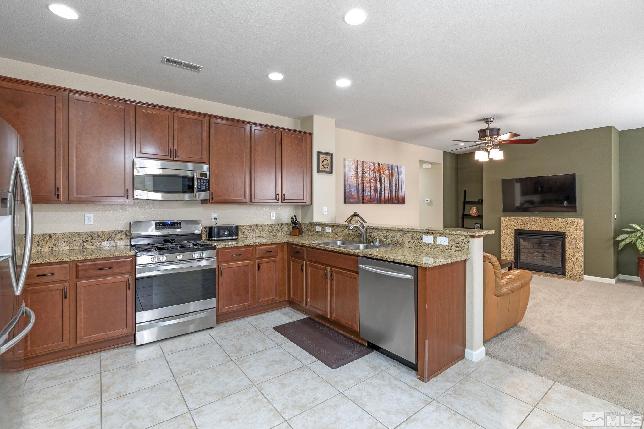 10848 Oakhaven Drive Reno, NV 89521 - Photo 16 of 32 a kitchen with stainless steel appliances granite countertop a stove top oven a sink dishwasher and a refrigerator with cabinets