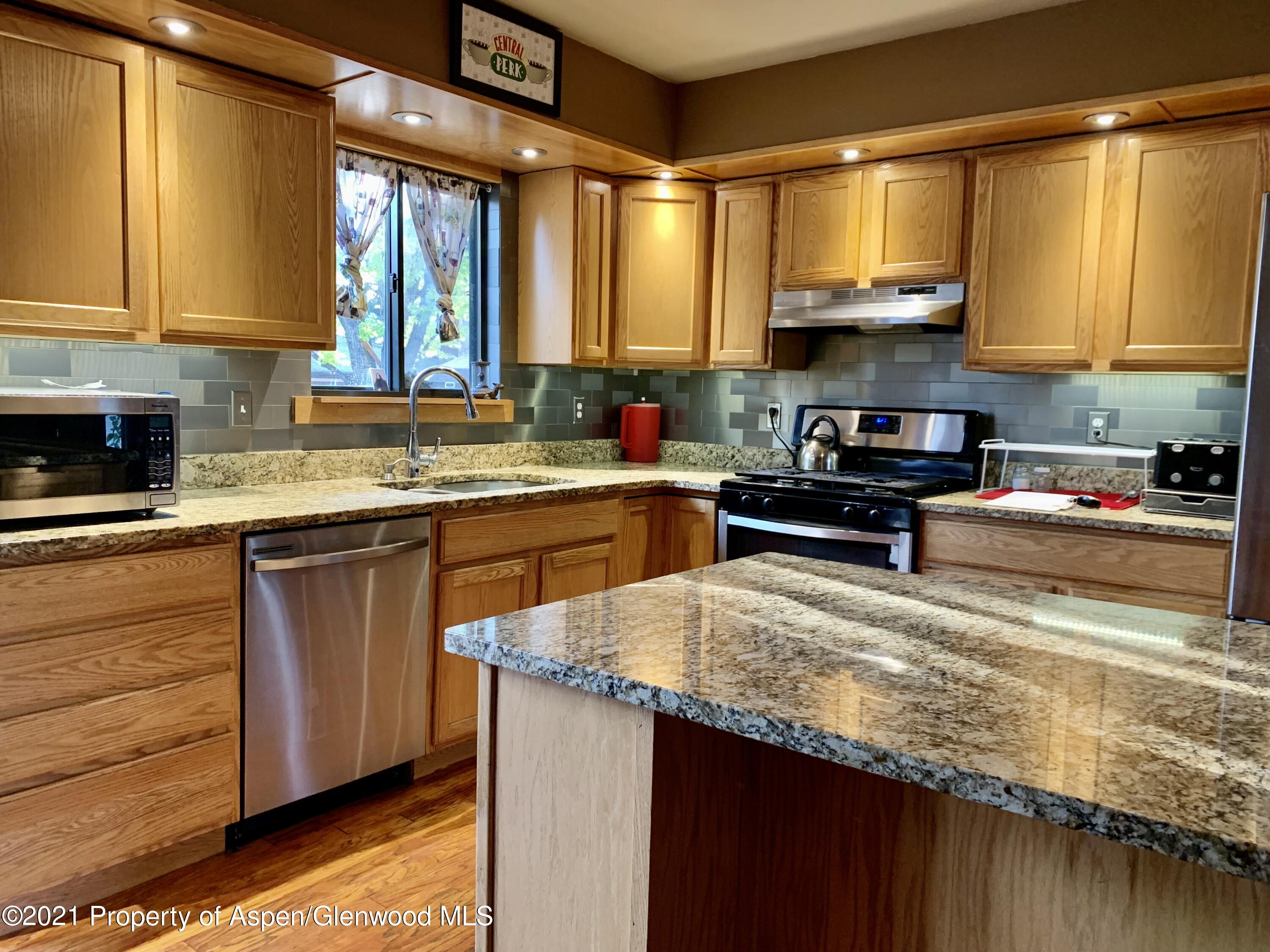 615 Ash Avenue Rifle, CO 81650 - Photo 3 of 24 a kitchen with kitchen island granite countertop a sink appliances cabinets and a counter top space