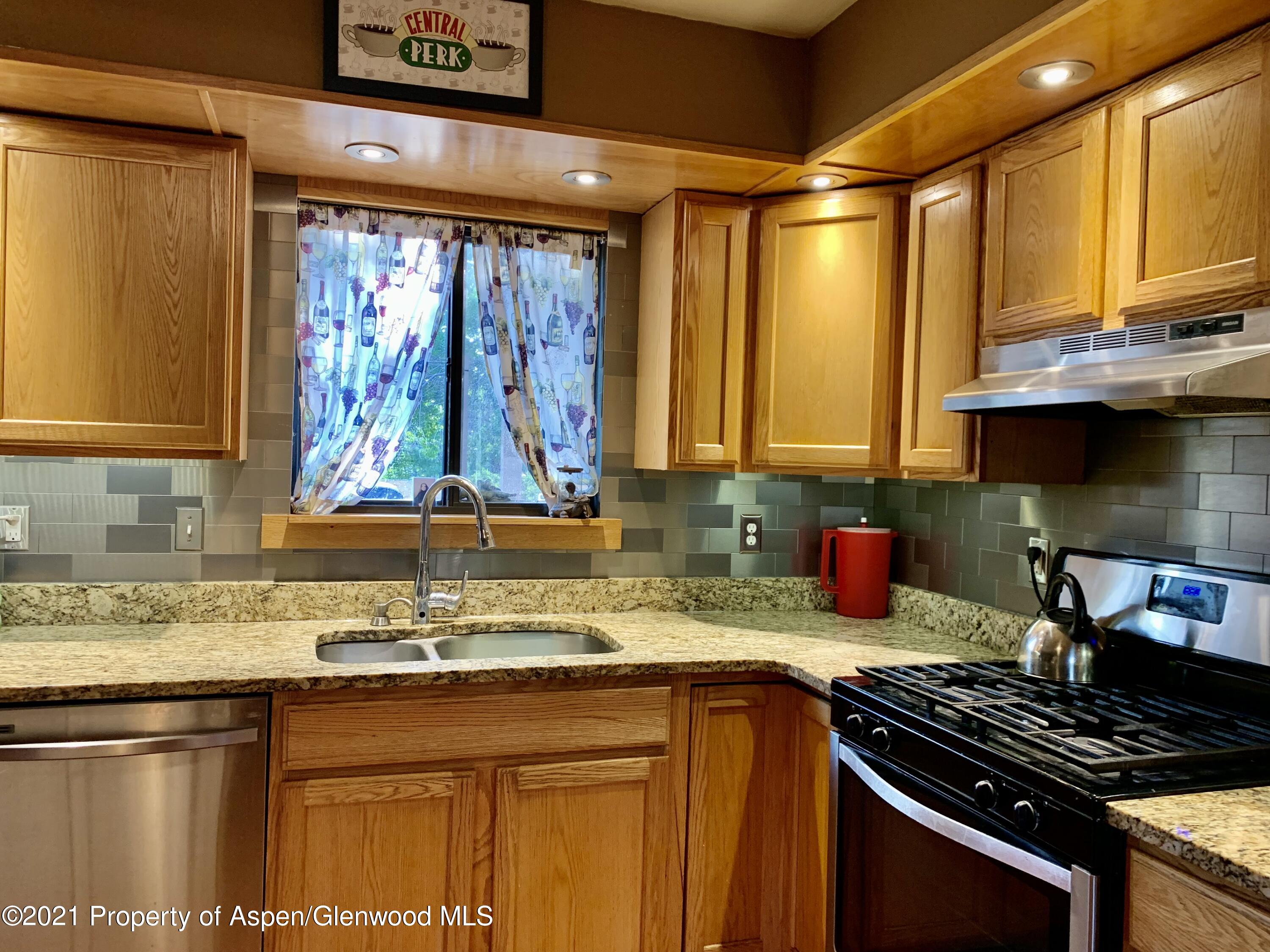 615 Ash Avenue Rifle, CO 81650 - Photo 4 of 24 a kitchen with stainless steel appliances granite countertop a sink a stove and a microwave