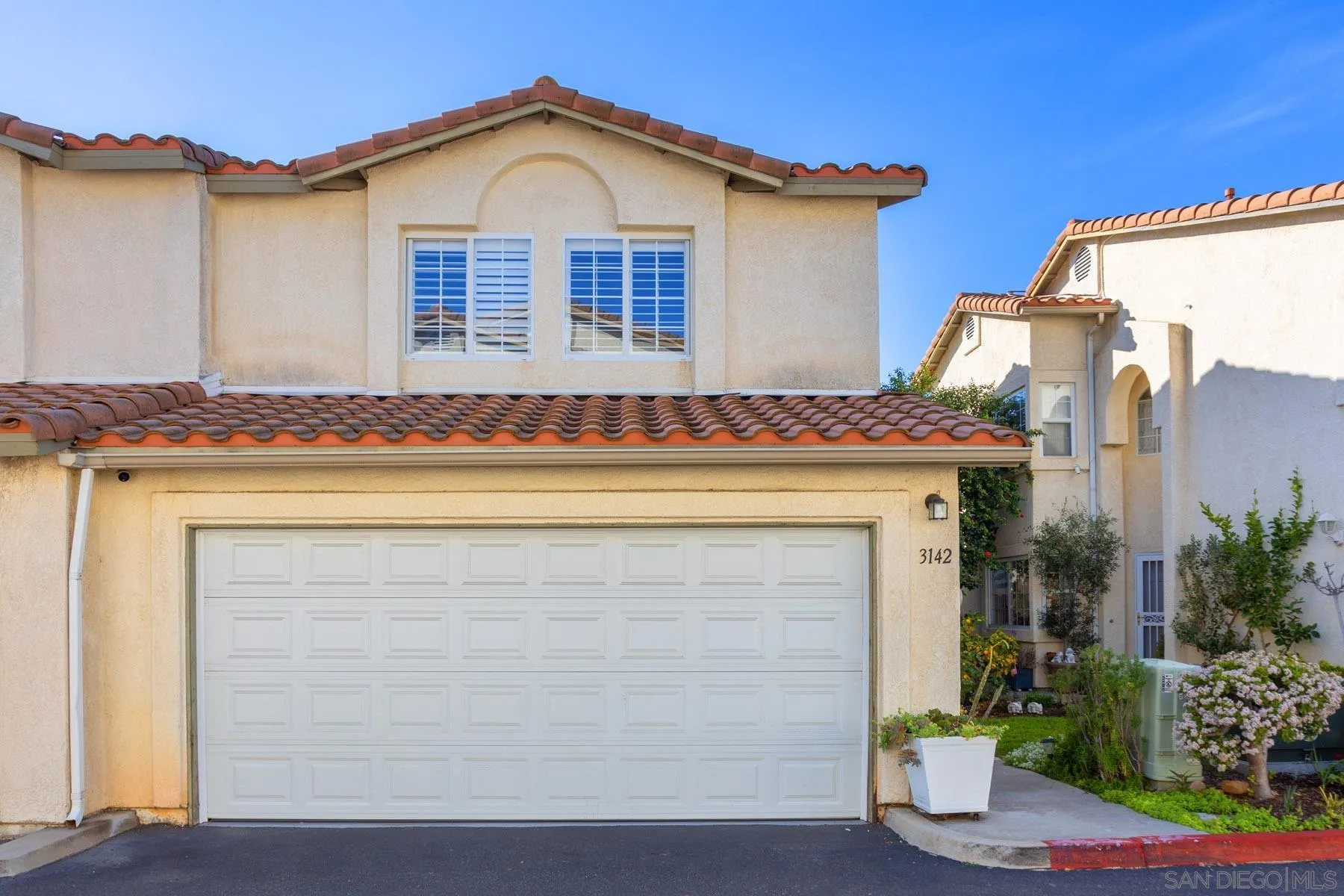 a view of a house with a yard and potted plants
