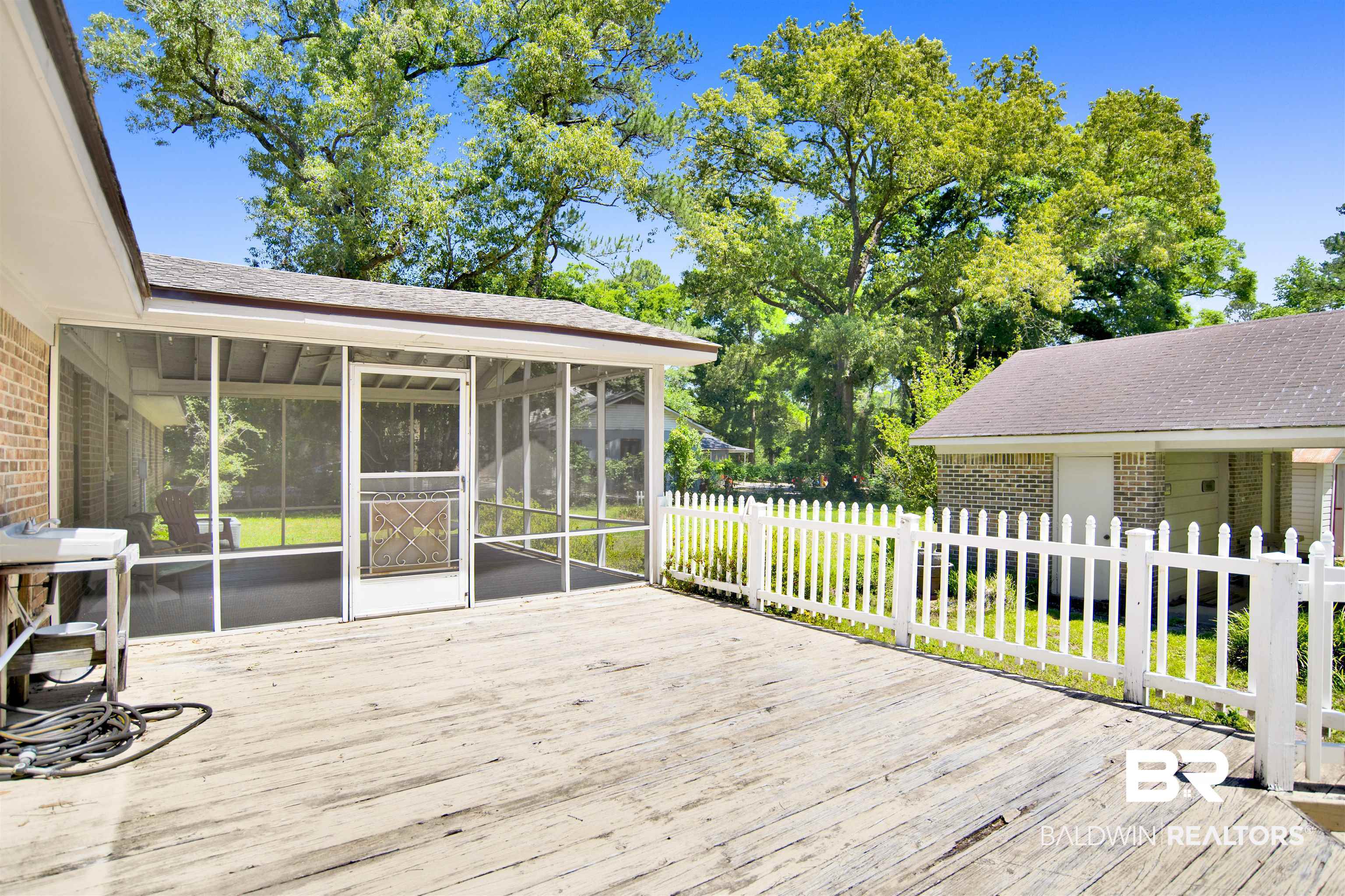 30888 Cemetery Road Daphne, AL 36527 - Photo 24 of 36 Expansive outdoor deck featuring a screened porch, white picket fence, and mature trees