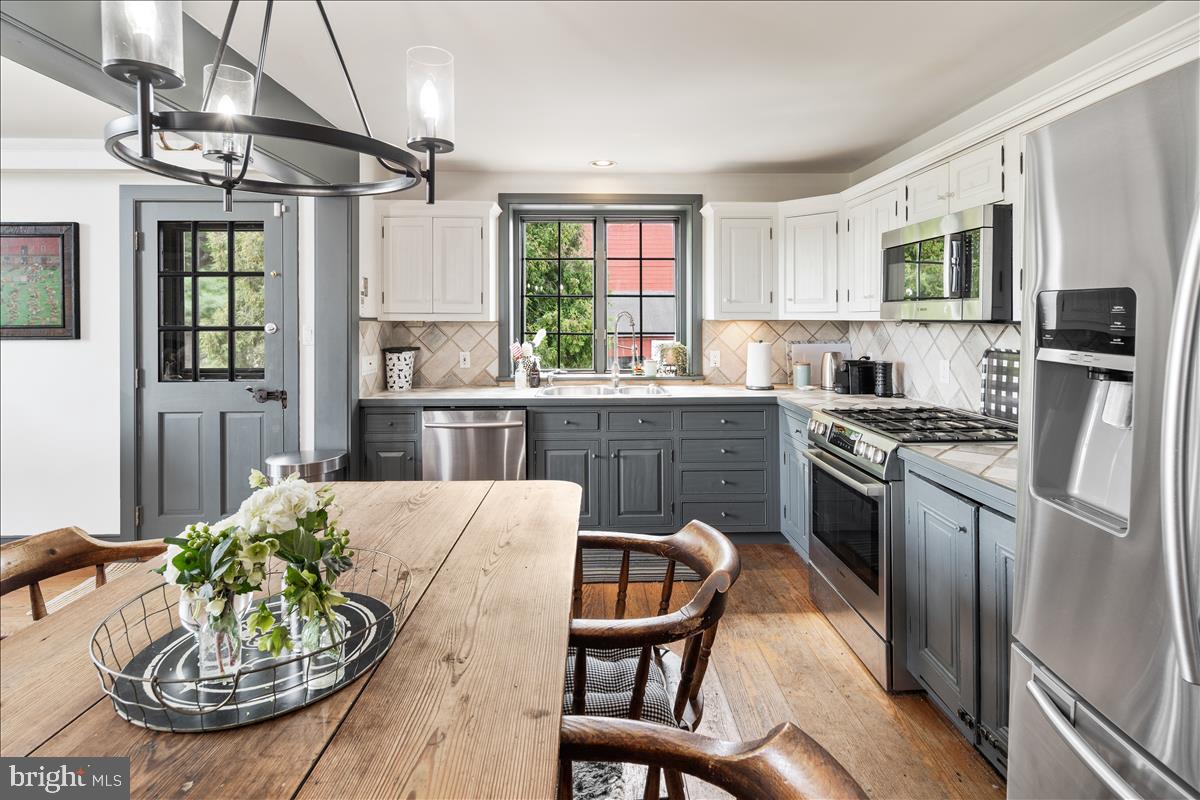 2753 Rushland Road Jamison, PA 18929 - Photo 8 of 60 a kitchen with stainless steel appliances granite countertop a stove a refrigerator a dining table and chairs with wooden floor