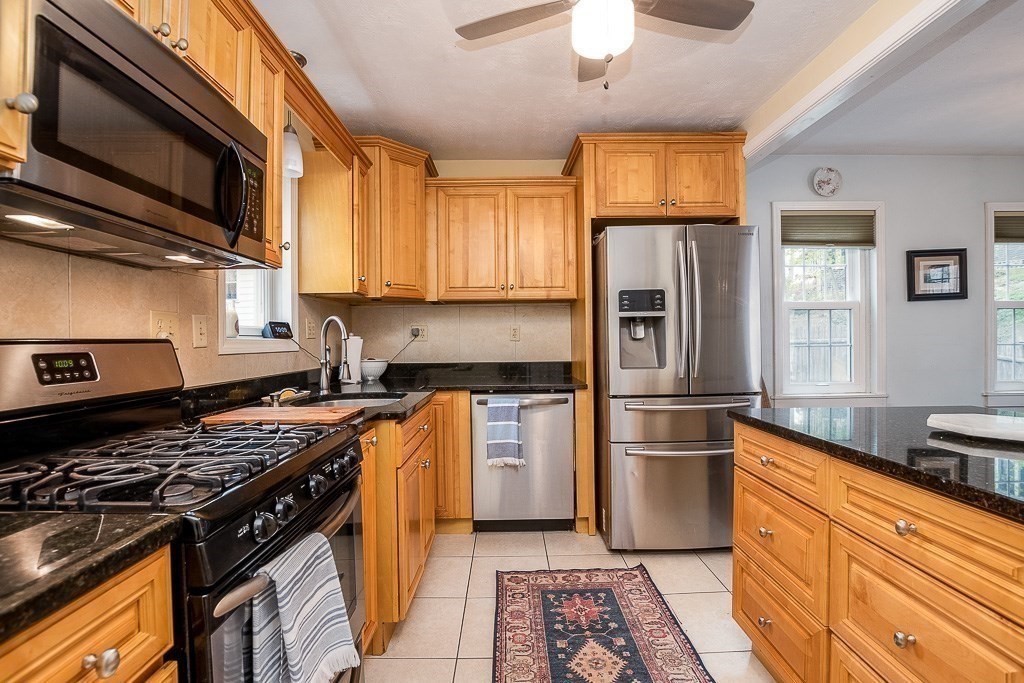 217 Lawrence Street Canton, MA 02021 - Photo 9 of 34 a kitchen with stainless steel appliances granite countertop a stove top oven a refrigerator a sink and dishwasher with wooden floor
