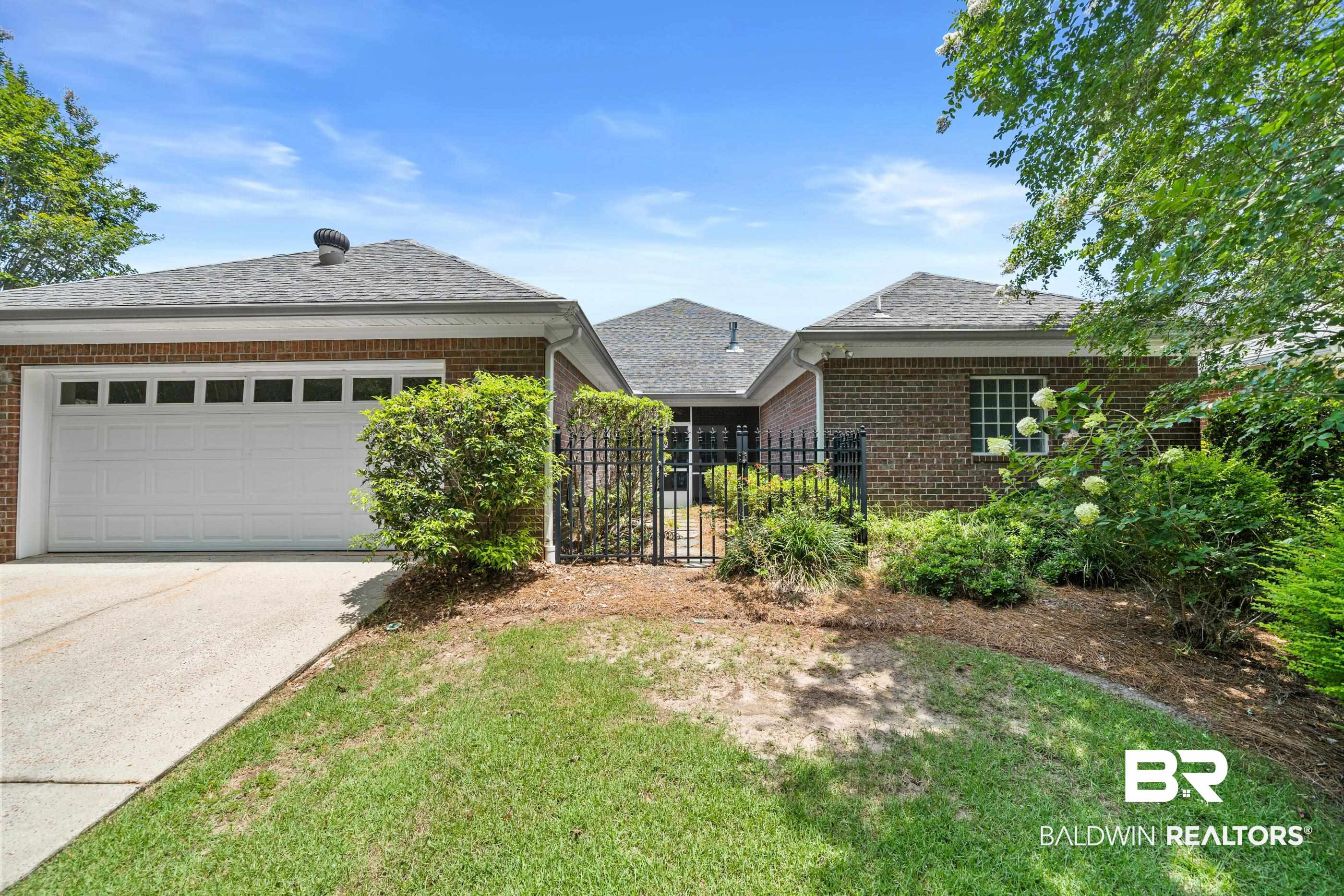 303 Savannah Circle Foley, AL 36535 - Photo 29 of 34 Brick exterior home featuring a two-car garage with a concrete driveway, a gabled roof, and mature landscaping