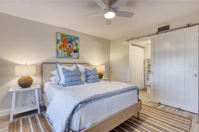 a bedroom with a bed a painting on the wall and a rug