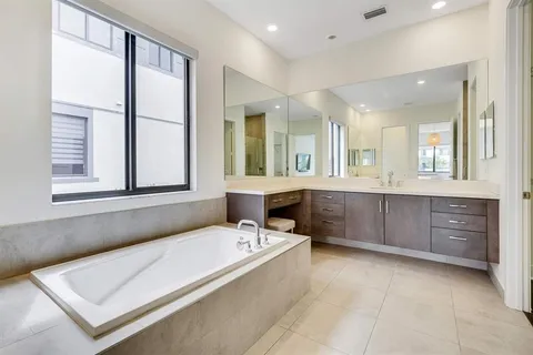 a bathroom with a tub a sink and a large mirror