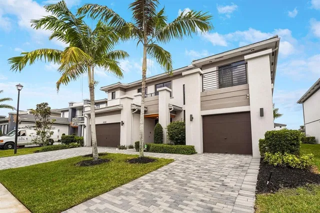a view of a white house with a yard and palm trees