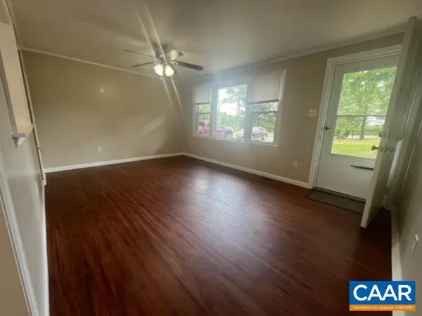 an empty room with wooden floor and windows