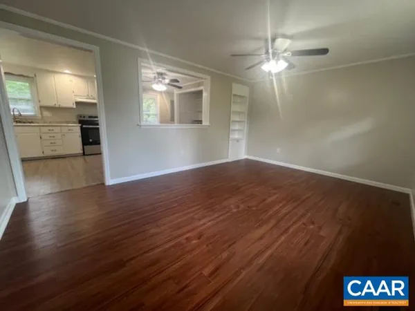 a view of a room with wooden floor and a kitchen