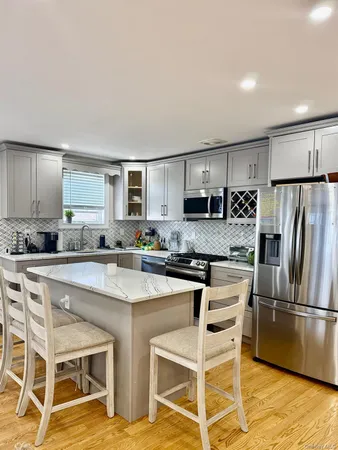 a kitchen with stainless steel appliances granite countertop a stove a sink dishwasher a refrigerator with cabinets table and chairs