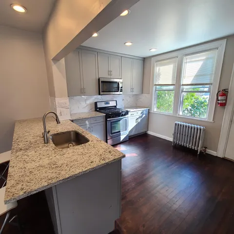 a kitchen with granite countertop a sink a counter top space and cabinets