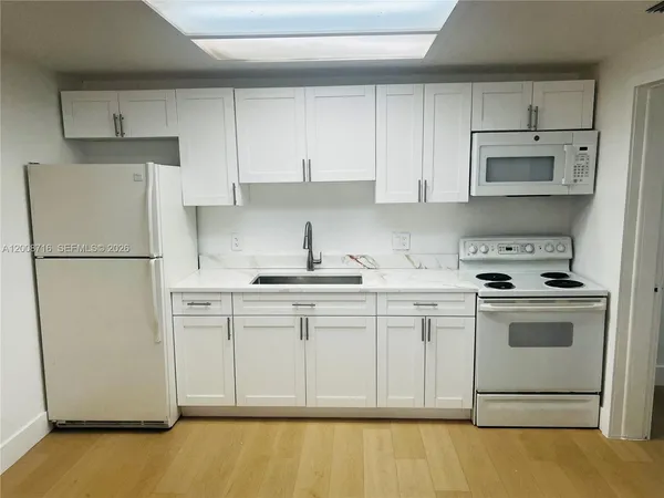 a kitchen with stainless steel appliances granite countertop a refrigerator sink stove and white cabinets