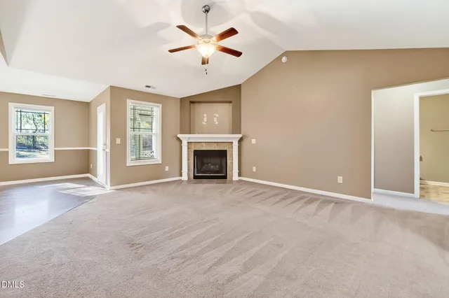 an empty room with windows and fireplace