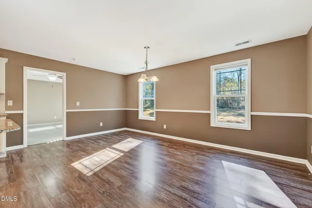 a view of an empty room with window and wooden floor