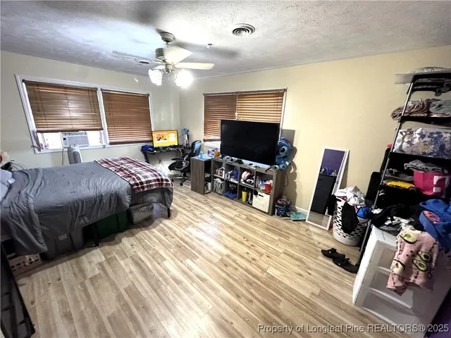 a bedroom with bed a flat tv screen and a dresser