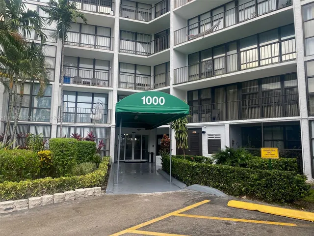 a front view of a building with a garden and plants