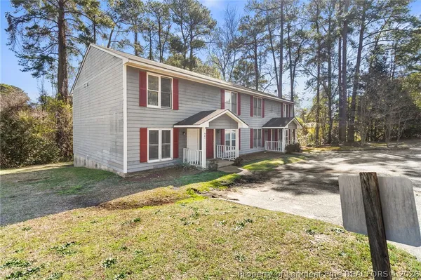 a view of a white house next to a yard with large trees